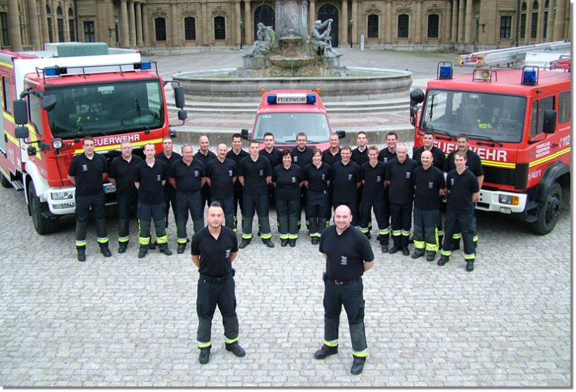 Gruppenbild Mannschaft mit drei Fahrzeugen vor Residenz